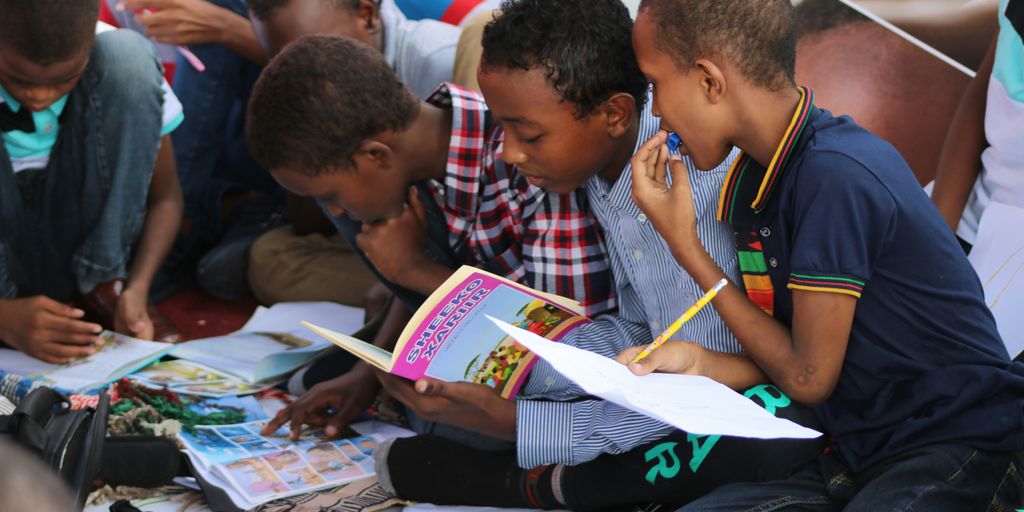 boy in blue and white plaid shirt reading book