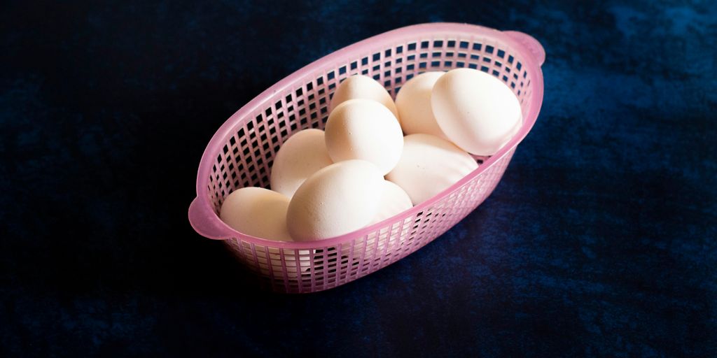 a pink basket filled with white eggs on top of a table