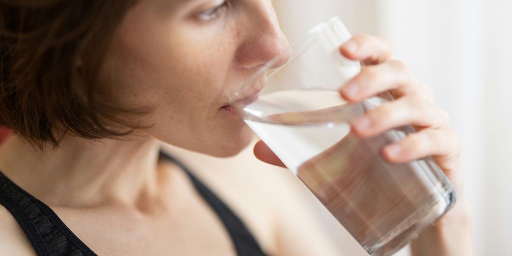 woman in black tank top drinking water